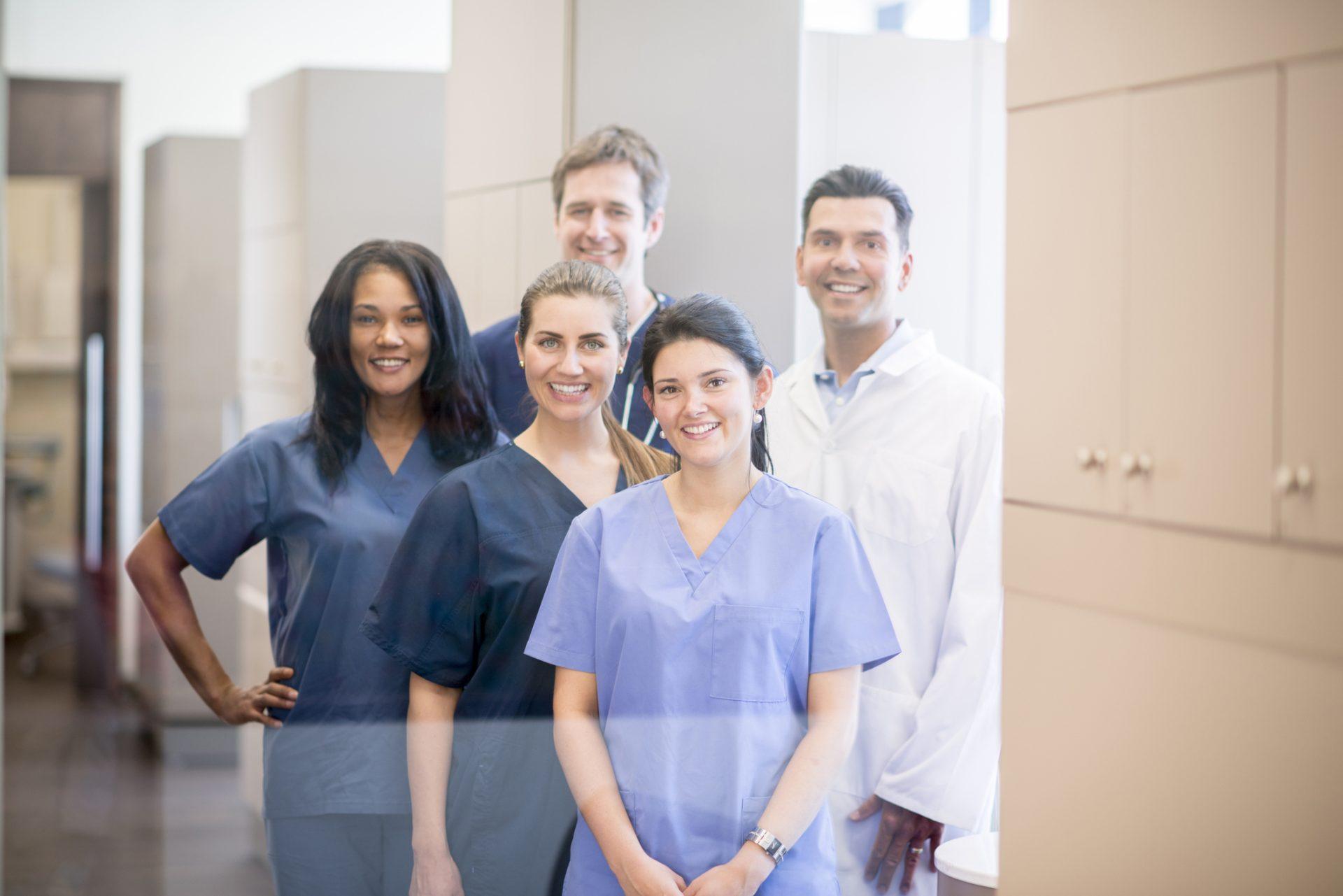 A group of doctors, nurses, and or dentists and professional assistants posing for a picture in a medical clinic.